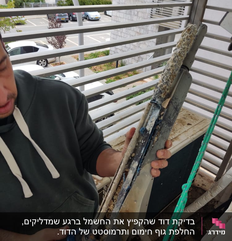 אדם מחזיק גוף חימום עם אבנית